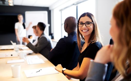 Female white executive smiling at camera during work presentation in office conference room