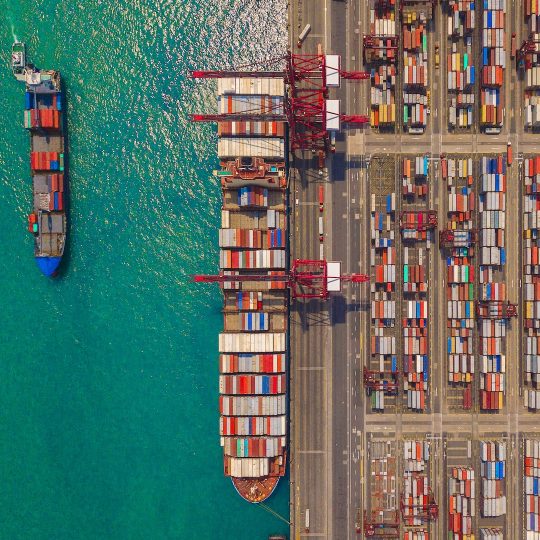 Aerial top view of container cargo ship in the export and import business and logistics international goods in urban city. Shipping to the harbor by crane in Victoria Harbour, Hong Kong.