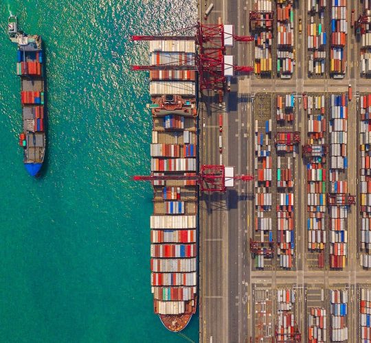 Aerial top view of container cargo ship in the export and import business and logistics international goods in urban city. Shipping to the harbor by crane in Victoria Harbour, Hong Kong.