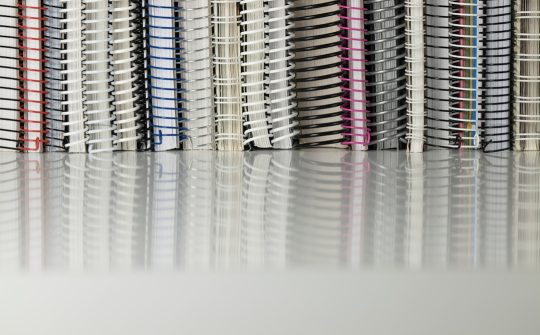 Still life of spiral notebooks on white table with reflection